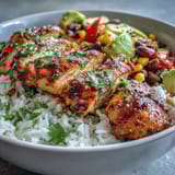 Golden Cajun-spiced chicken slices rest on fluffy white rice beside colorful peppers, sweet corn, and black beans.