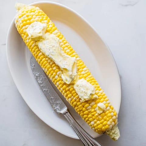 Perfectly boiled corn on the cob, dripping with creamy butter, served warm as a classic American side.