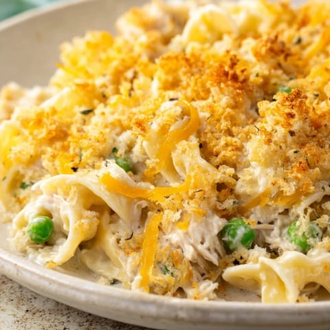 Hot tuna casserole scooped from dish, served with side salad for family dinner.