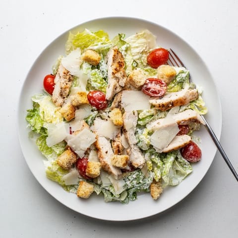 Golden-brown grilled chicken strips sliced over a crisp bed of romaine lettuce, topped with shaved Parmesan and croutons for the Yogurt Caesar Grilled Chicken Salad.