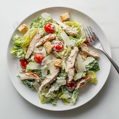 A close-up view of creamy Greek yogurt Caesar dressing drizzled over tender grilled chicken and fresh romaine for the Yogurt Caesar Grilled Chicken Salad.