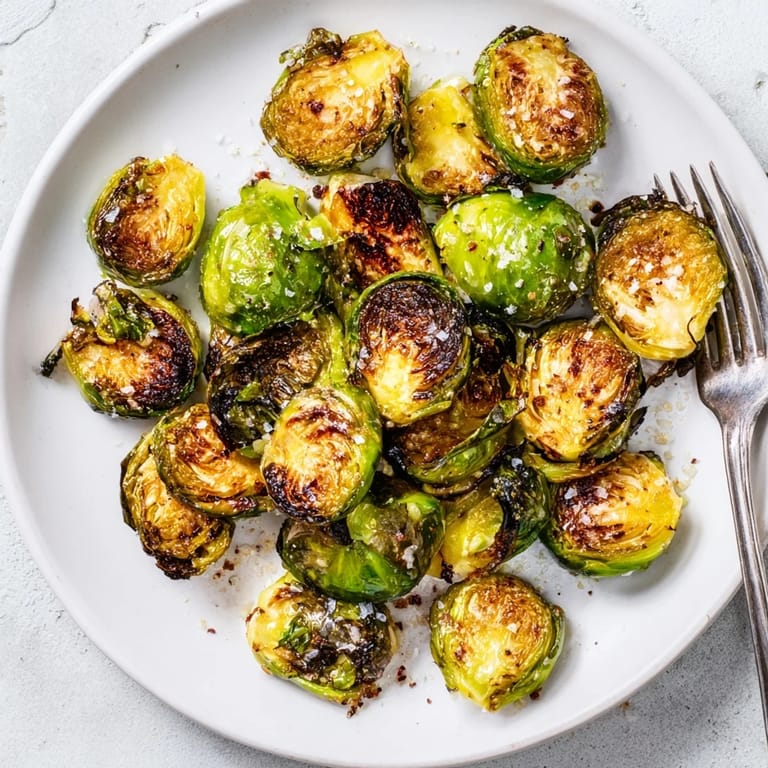 Freshly roasted Roasted Brussels Sprouts served in a white bowl, glistening with olive oil, ready to be eaten hot.