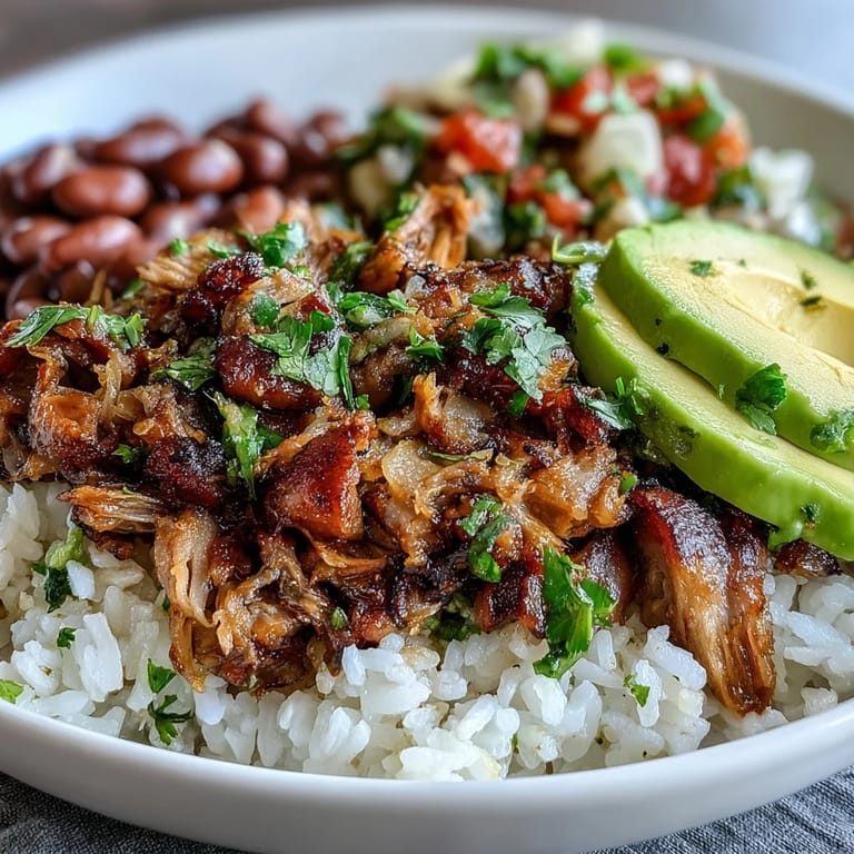 A colorful Mexican-inspired Carnitas Bowl with seasoned rice, hearty pinto beans, shredded carnitas, fresh cilantro, and pico de gallo, ready to enjoy.